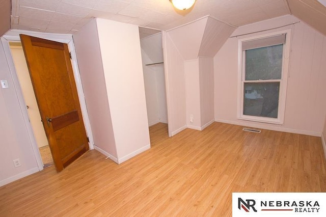 additional living space with light hardwood / wood-style floors and vaulted ceiling