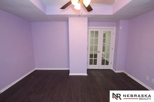 spare room with french doors, dark hardwood / wood-style flooring, a raised ceiling, and ceiling fan