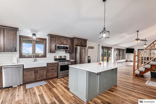 kitchen featuring appliances with stainless steel finishes, tasteful backsplash, vaulted ceiling, sink, and a center island