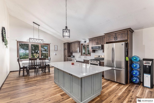 kitchen featuring pendant lighting, a center island, decorative backsplash, dark brown cabinetry, and stainless steel appliances