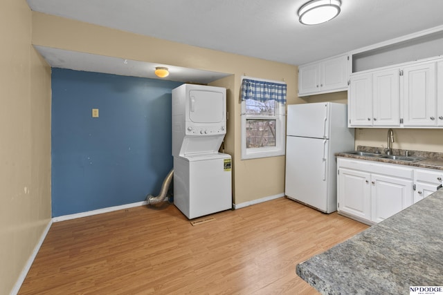 kitchen with white cabinetry, sink, light hardwood / wood-style flooring, white refrigerator, and stacked washer and dryer