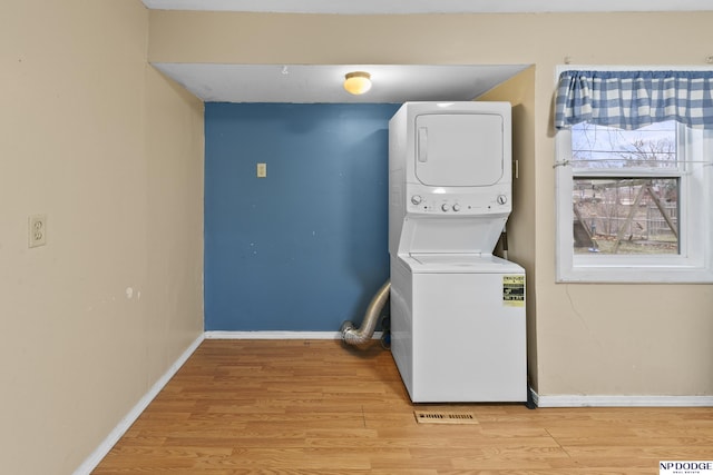 washroom with stacked washer / drying machine and light wood-type flooring