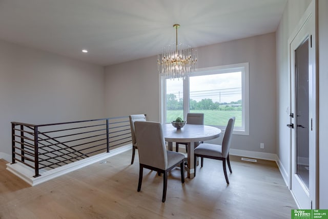 dining space with light wood-type flooring and a chandelier