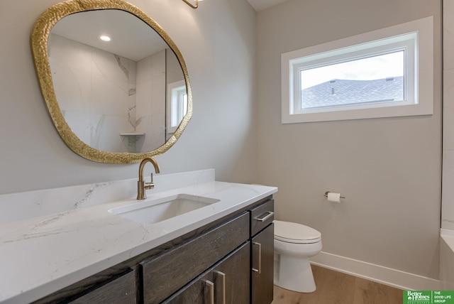 bathroom with hardwood / wood-style flooring, vanity, toilet, and a shower