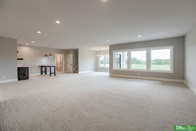 unfurnished living room with light carpet and a notable chandelier