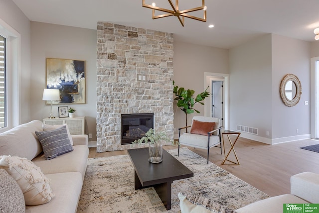 living room with a fireplace, light wood-type flooring, and a chandelier