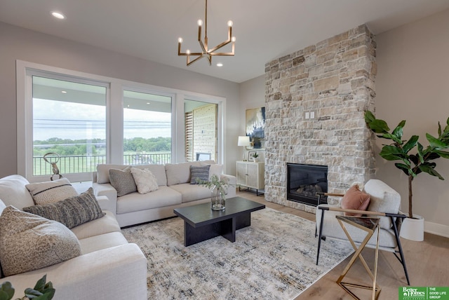 living room with a fireplace, light wood-type flooring, plenty of natural light, and a notable chandelier