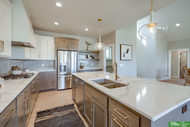 kitchen with sink, decorative light fixtures, a kitchen island with sink, custom range hood, and appliances with stainless steel finishes