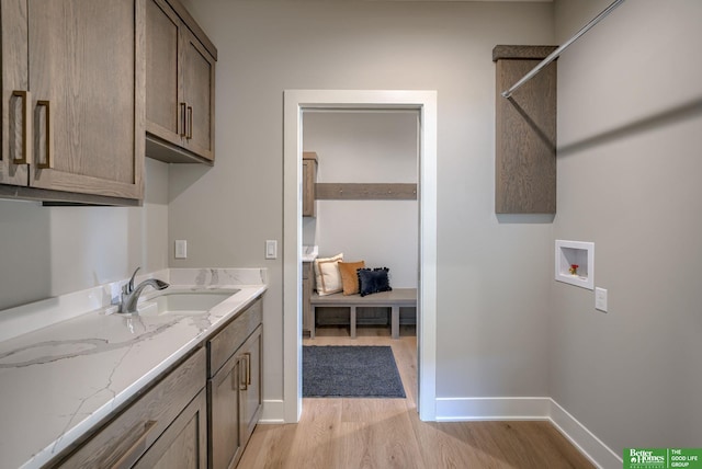 washroom with cabinets, washer hookup, light wood-type flooring, and sink