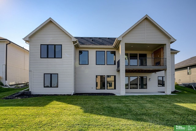 back of property with a lawn, a patio area, and a balcony