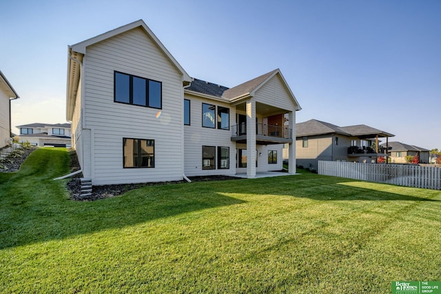 rear view of property featuring a balcony, a yard, and a patio