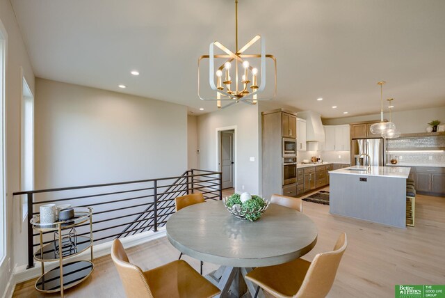 dining area with a notable chandelier, light wood-type flooring, and sink