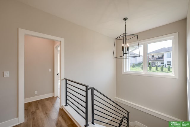 stairs with hardwood / wood-style flooring and a notable chandelier