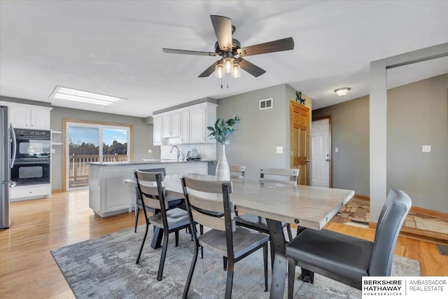 dining room with ceiling fan, light wood-type flooring, and sink