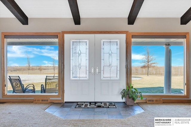 foyer featuring carpet, plenty of natural light, and beam ceiling