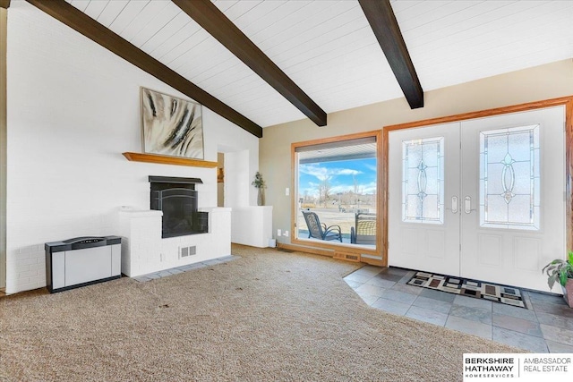 foyer entrance featuring vaulted ceiling with beams, light carpet, a fireplace, and french doors