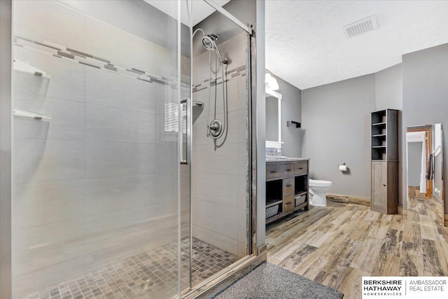 bathroom with vanity, a textured ceiling, wood-type flooring, toilet, and a shower with shower door