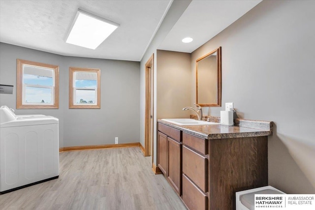 washroom with cabinets, sink, light hardwood / wood-style floors, and washer / dryer