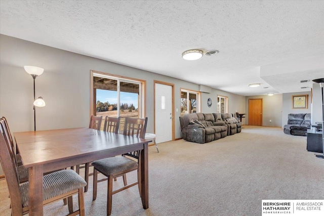 dining space featuring a textured ceiling and light colored carpet