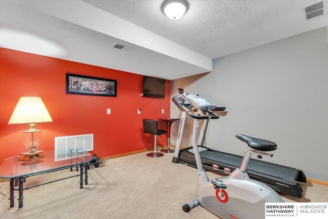 exercise room with carpet flooring and a textured ceiling