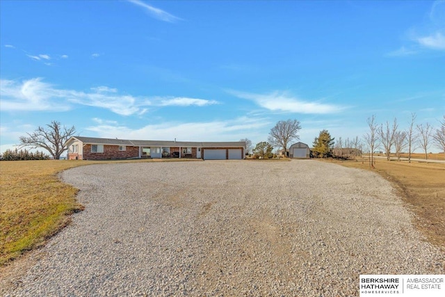 single story home with a rural view, a shed, and a garage