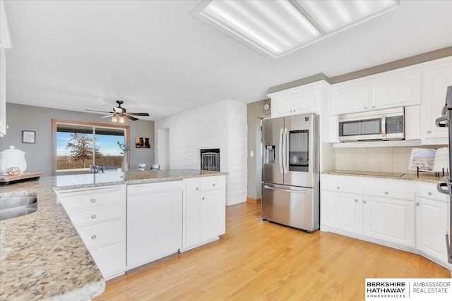 kitchen featuring ceiling fan, light wood-type flooring, appliances with stainless steel finishes, light stone counters, and white cabinetry