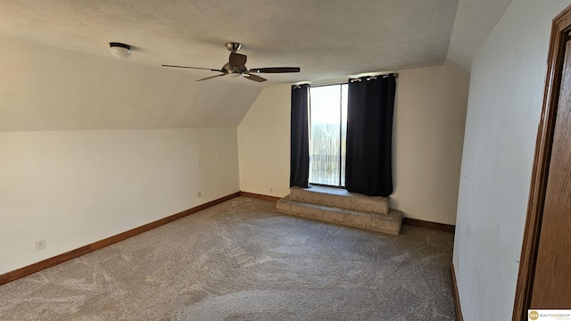 additional living space with a textured ceiling, carpet floors, vaulted ceiling, and ceiling fan