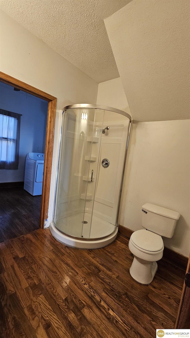 bathroom with washer / clothes dryer, a shower with door, wood-type flooring, and a textured ceiling