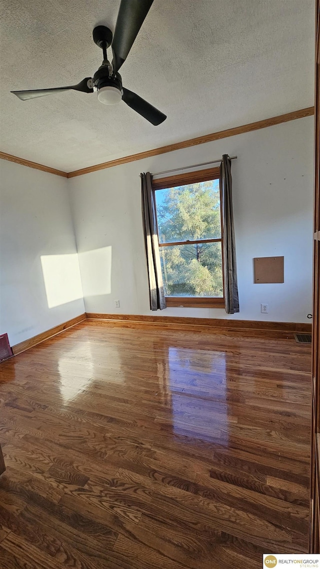 spare room with ornamental molding, a textured ceiling, ceiling fan, and dark wood-type flooring