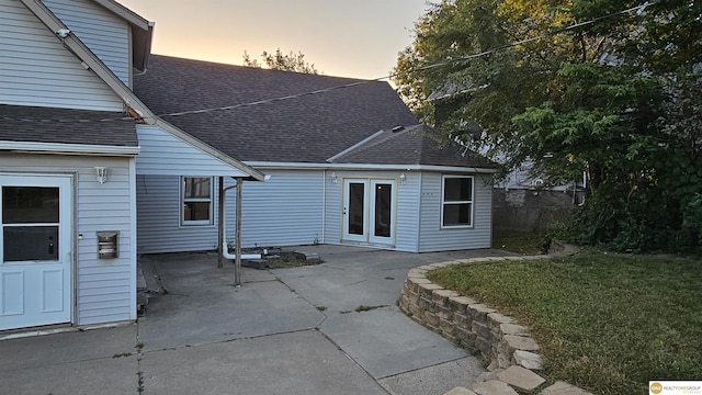 back house at dusk with a patio area and a yard