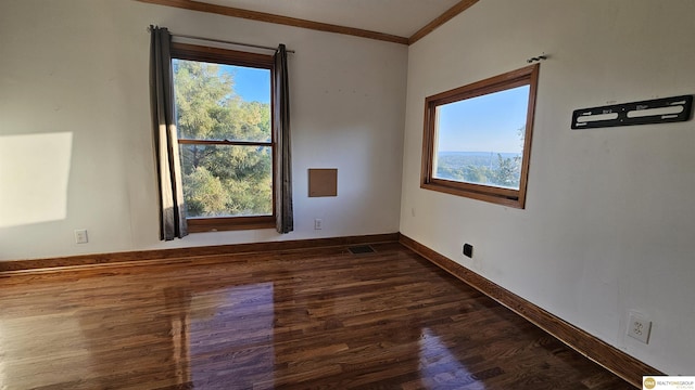 empty room featuring dark hardwood / wood-style flooring, crown molding, and a healthy amount of sunlight