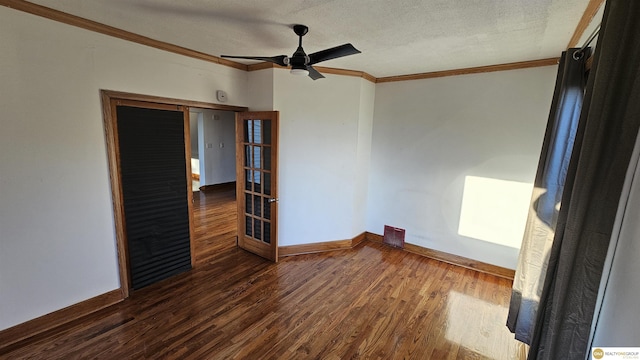 empty room with dark hardwood / wood-style flooring, ornamental molding, a textured ceiling, and french doors