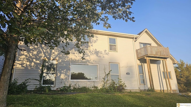 rear view of house featuring a yard and a balcony