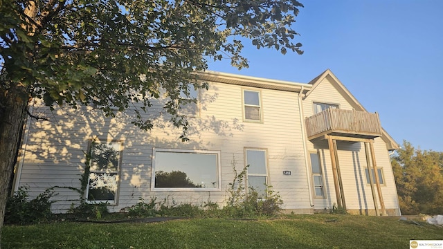 back of house with a balcony and a lawn