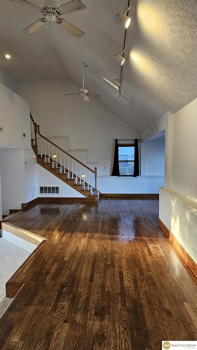 interior space with wood-type flooring, a textured ceiling, vaulted ceiling, and ceiling fan