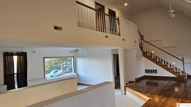 stairway with hardwood / wood-style flooring, ceiling fan, and a towering ceiling