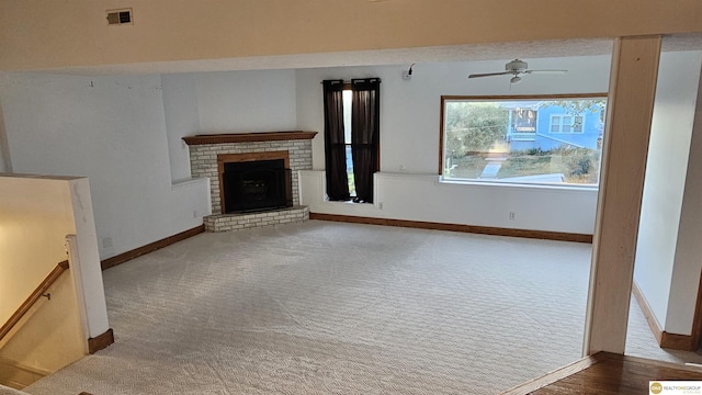 unfurnished living room featuring carpet floors, a brick fireplace, and ceiling fan