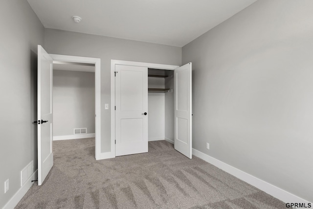 unfurnished bedroom with light carpet and a closet