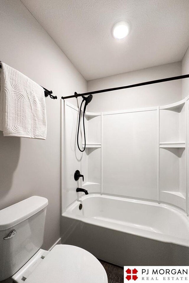 bathroom with a textured ceiling, toilet, and shower / washtub combination