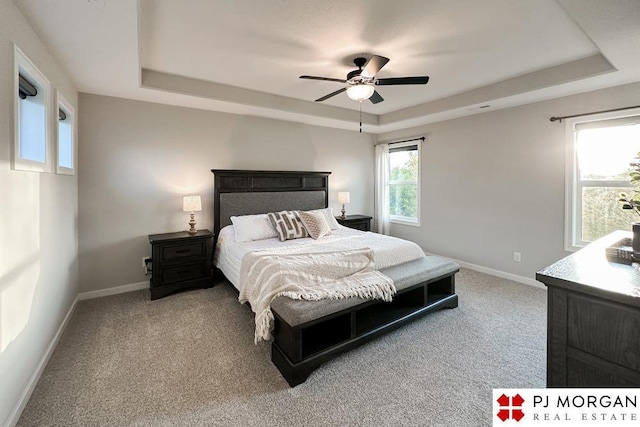 carpeted bedroom featuring ceiling fan and a raised ceiling