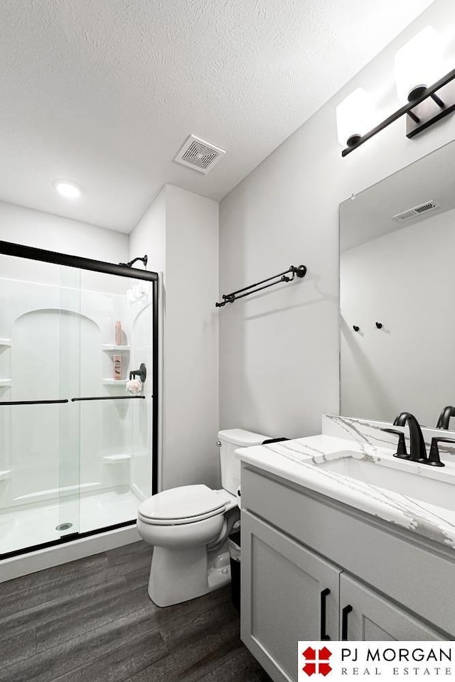 bathroom with hardwood / wood-style floors, vanity, a textured ceiling, and walk in shower