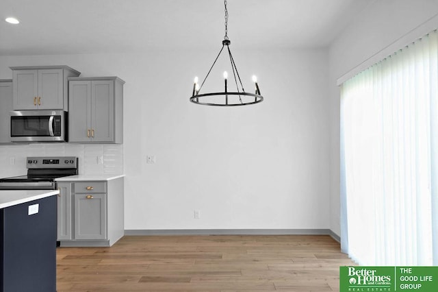 kitchen with backsplash, light hardwood / wood-style floors, pendant lighting, gray cabinets, and appliances with stainless steel finishes