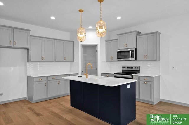 kitchen with backsplash, gray cabinetry, an island with sink, and stainless steel appliances