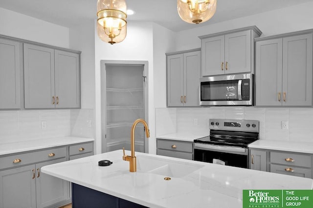 kitchen featuring hanging light fixtures, gray cabinets, sink, and stainless steel appliances