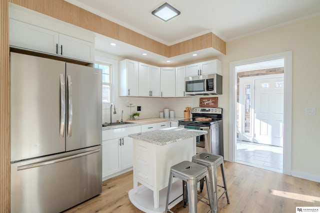 kitchen with a breakfast bar, a center island, white cabinetry, and appliances with stainless steel finishes