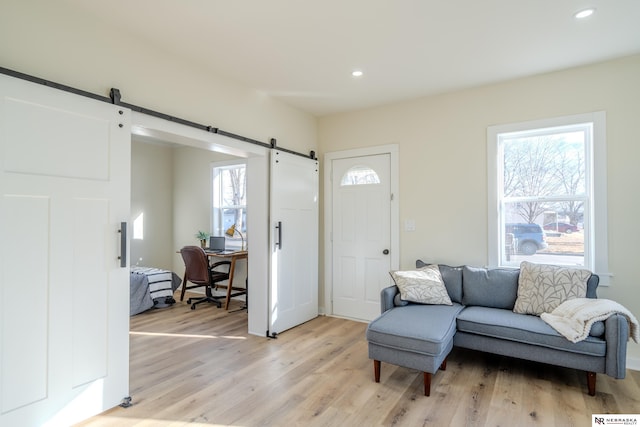 living room with a barn door and light wood-type flooring