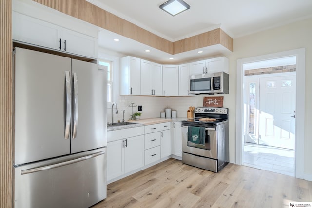 kitchen with sink, white cabinets, stainless steel appliances, and light wood-type flooring