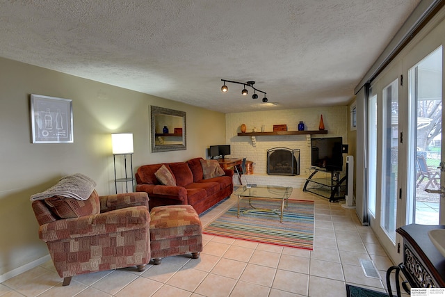 tiled living room with rail lighting, a textured ceiling, and a brick fireplace