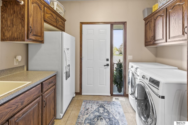 laundry room with washer and dryer, sink, light tile patterned floors, and cabinets