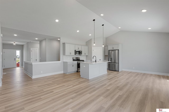 kitchen with hanging light fixtures, tasteful backsplash, a center island with sink, and stainless steel appliances